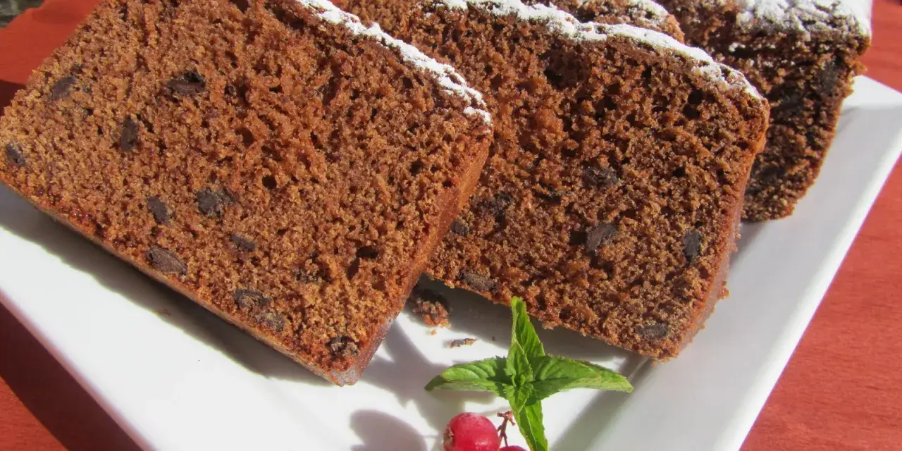Rebanadas de bizcocho de colacao con trocitos de chocolate, espolvoreado con azúcar glas y decorado con grosellas y menta.