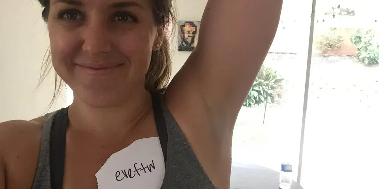 Kvinna visar sin armhåla, som har viss hyperpigmentering. En lapp med texten "eveftw" sitter på hennes bröst.