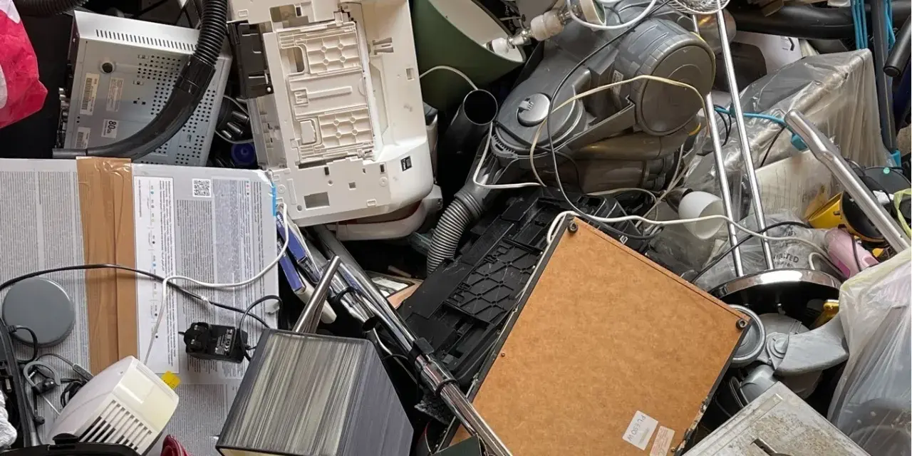 Stary sprzęt AGD, w tym odkurzacz i drukarka, tworzą stos. Zastanawiasz się, gdzie wyrzucić żelazko? To miejsce to idealny przykład elektrośmieci.