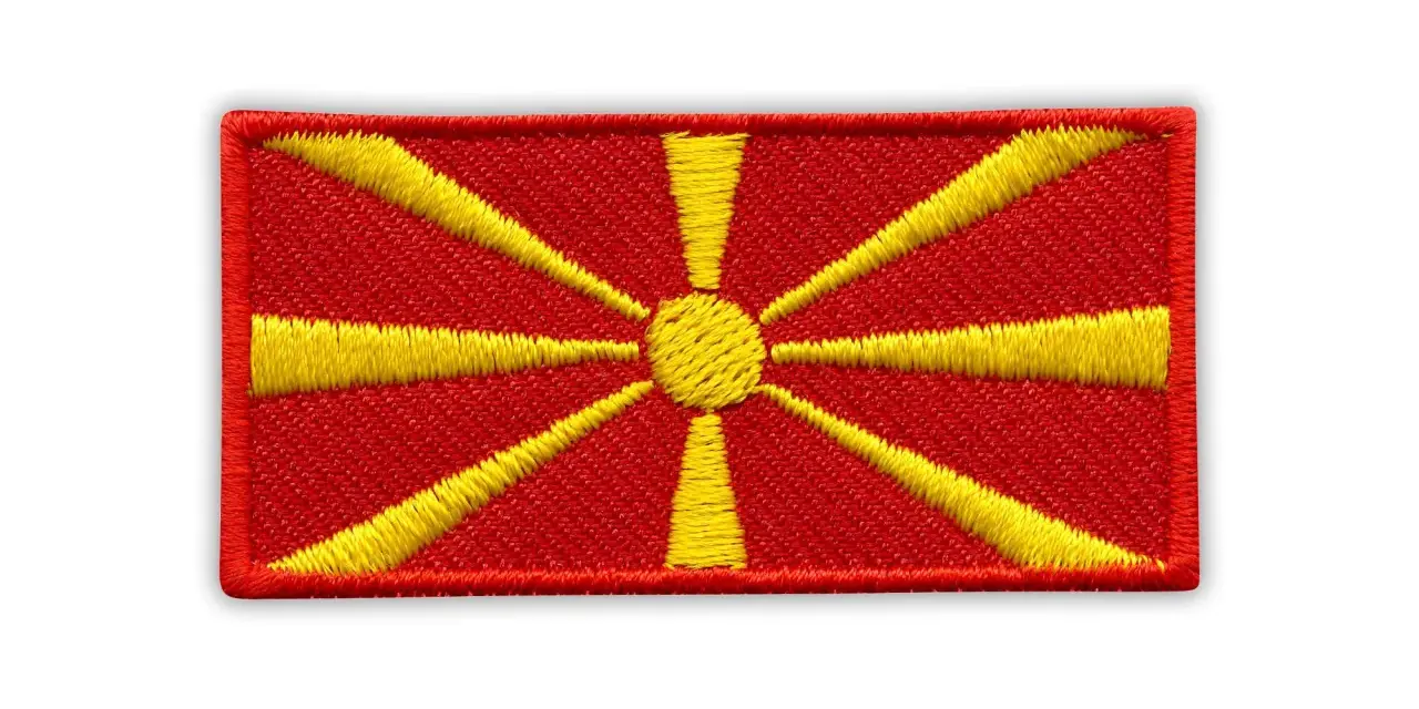 Naszywka z flagą Macedonii. Czerwone tło z żółtym słońcem i promieniami.