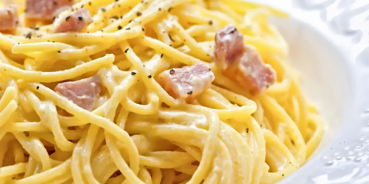 Un plato de pasta cremosa con trozos de panceta y pimienta negra molida, una auténtica carbonara original.