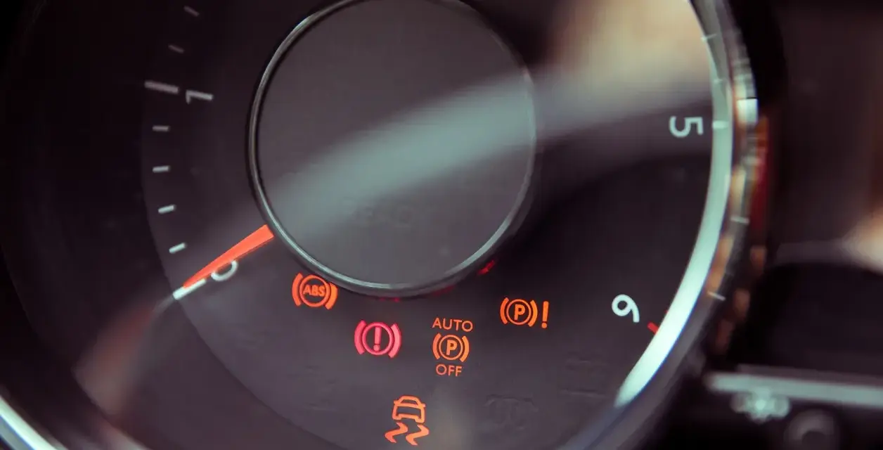 Dashboard lights illuminate, including ABS, brake warning, and a car skidding, indicating a potential issue with the slip indicator light.