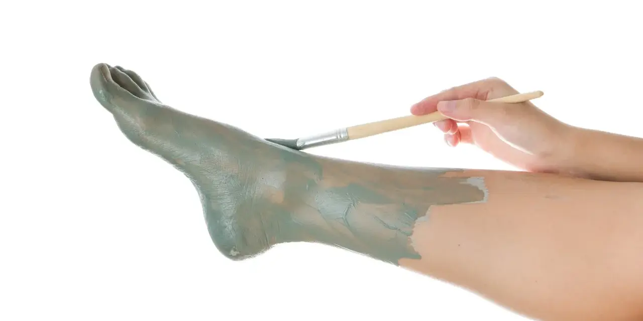 Application d'un masque d'argile sur un pied, comme un soin pour un clou au pied.