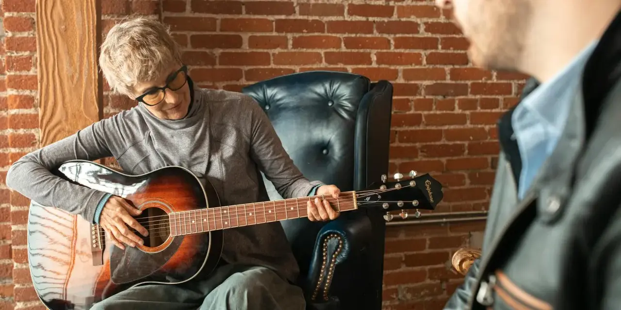Kobieta gra na gitarze w szkole muzycznej dla dorosłych. Lekcja z nauczycielem.
