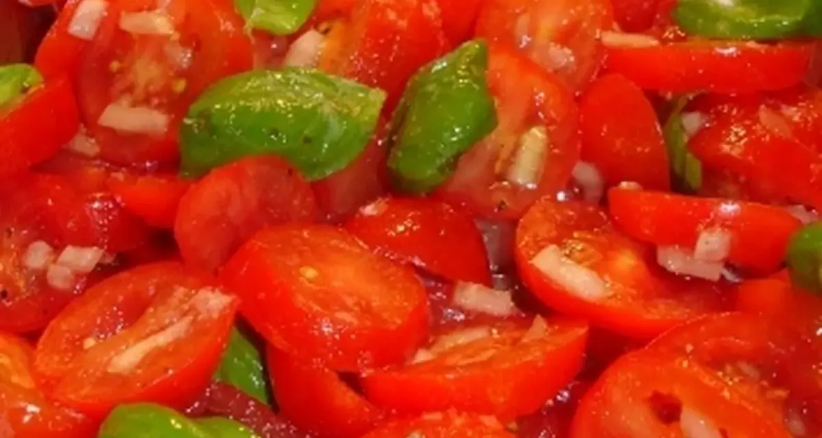 Frischer Tomatensalat mit Zwiebeln und Basilikum, bereit für ein leichtes Tomatensalat Dressing.