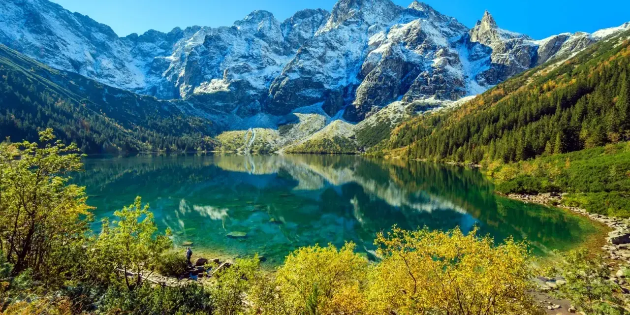 Piękny widok na Morskie Oko, gdzie szczyty górskie odbijają się w krystalicznie czystej wodzie. Ile się idzie na Morskie Oko? To zależy od tempa, ale widok wynagradza każdy krok.