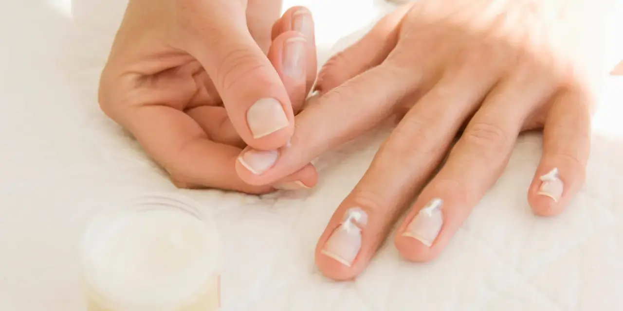 Application de crème pour hydrater la peau sèche autour des ongles.