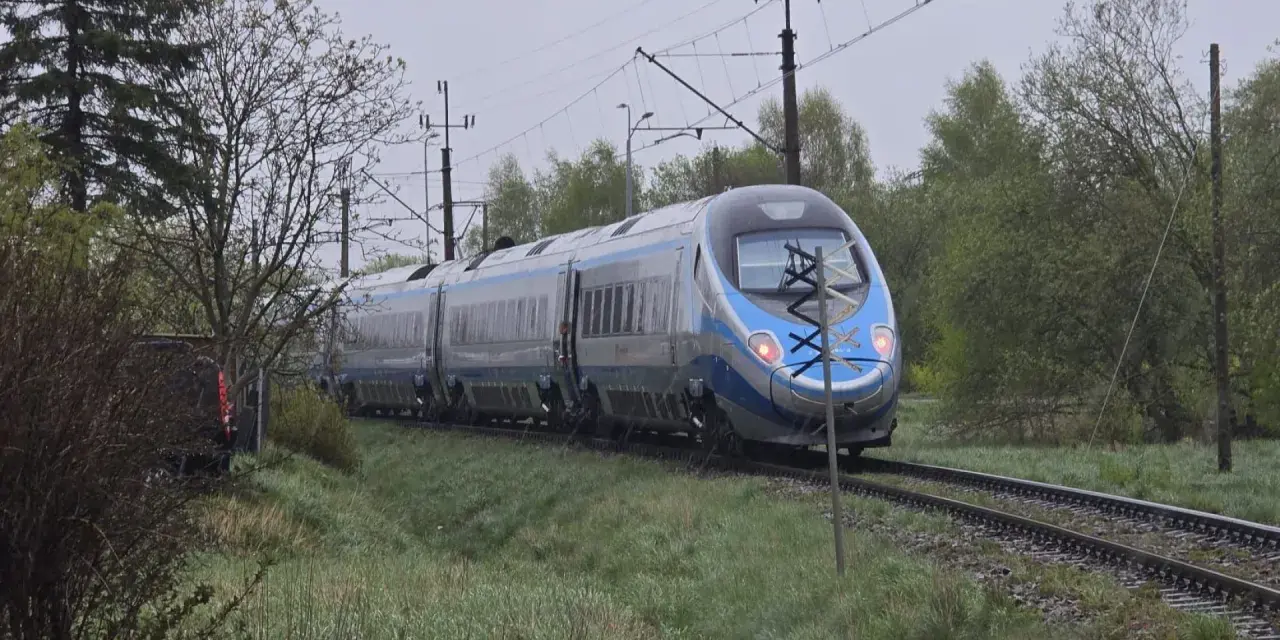 Srebrno-niebieski pociąg Pendolino jedzie po torach. W tle drzewa i słupy trakcyjne. Może to opóźnienie pociągu zwrot?