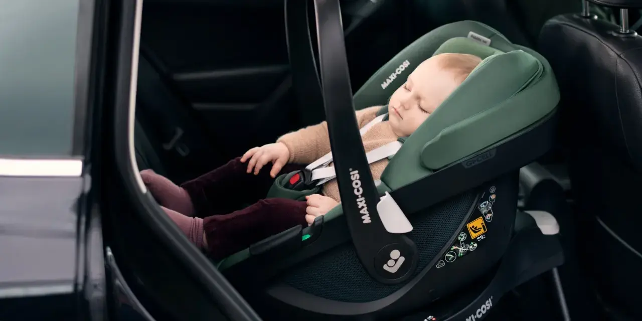 Schlafendes Baby in einer grünen Babyschale mit Isofix-Autobefestigung. Sicher und bequem auf Reisen.