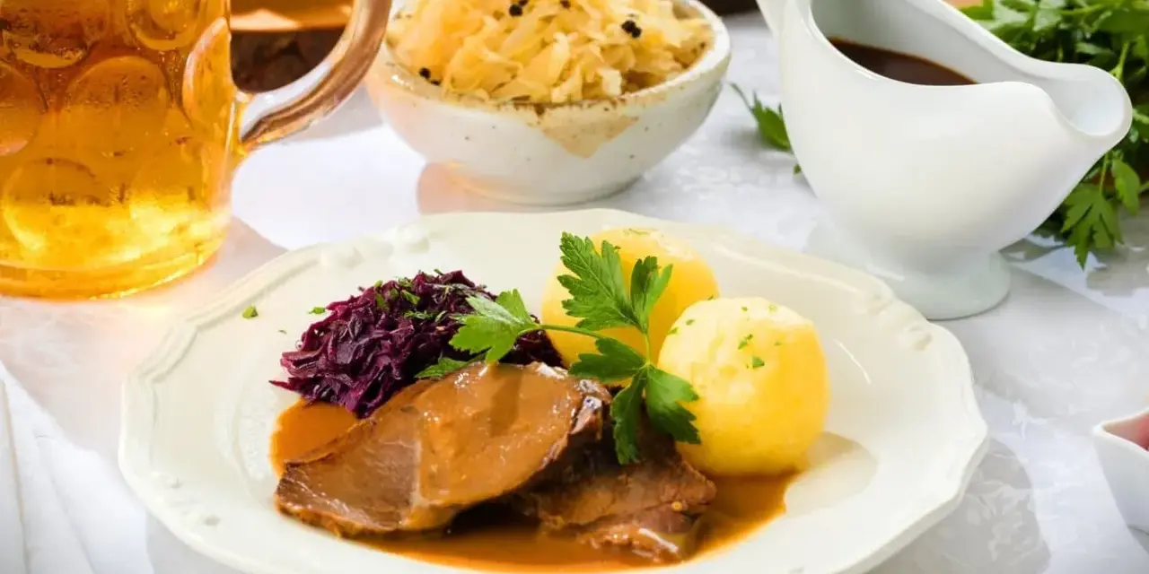 Deftiger Schweinebraten mit Klößen, Rotkohl und Sauerkraut. Dazu passt ein kühles Bier.