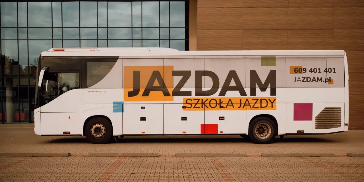 Biały autobus szkolny z napisem "JAZDAM SZKOŁA JAZDY" i numerem telefonu. Idealny do nauki jazdy kategorii D.