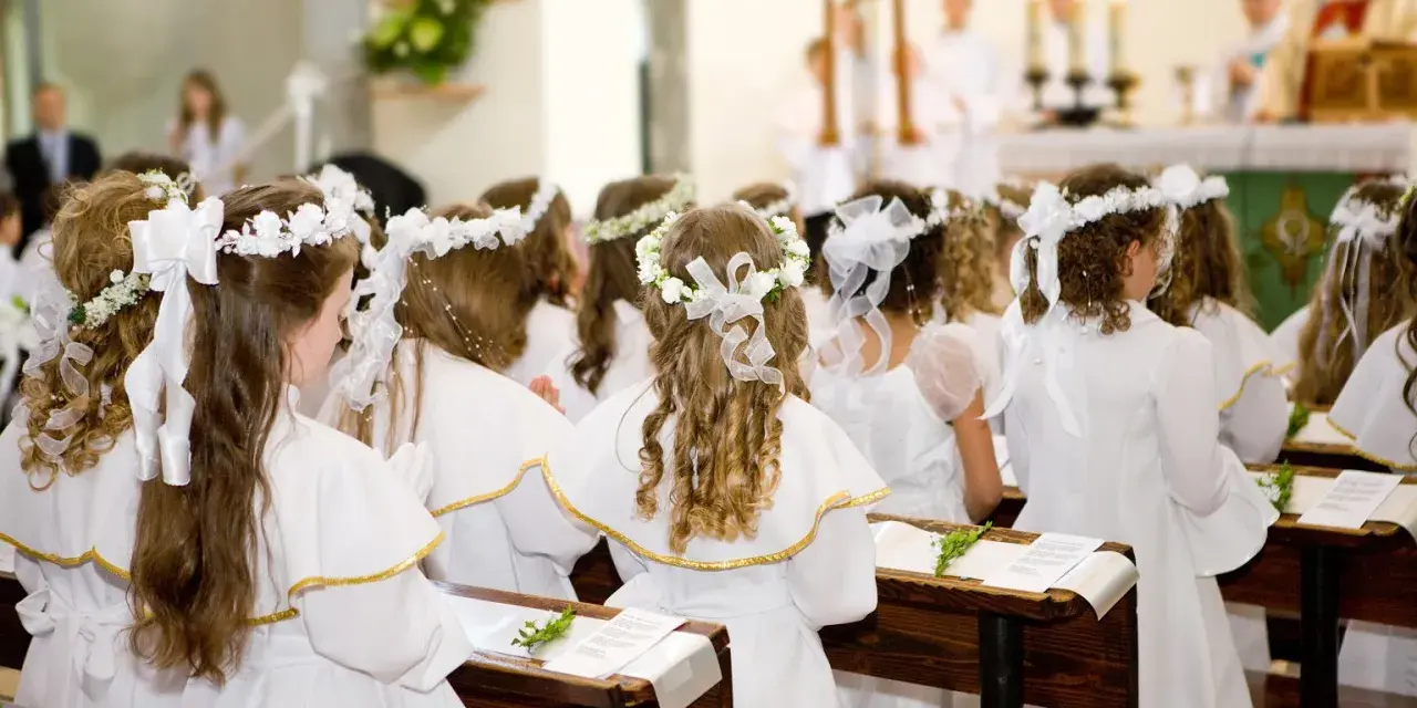 Dzieci w bieli, z wiankami na głowach, czekają na uroczystość. Piękne życzenia na komunie dla nich.