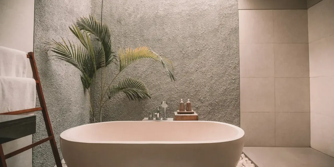 Ett modernt badrum med fristående badkar, en grå texturerad vägg och en palm. Perfekt för att renovera badrum och skapa en spa-känsla.
