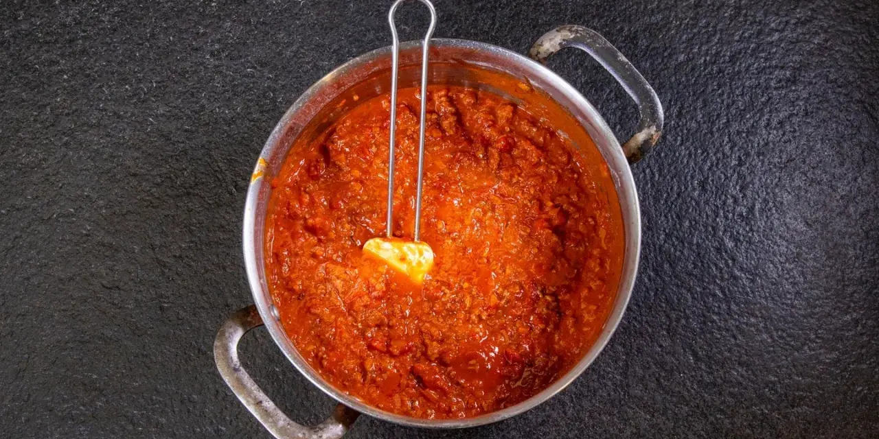 Herzhaftes Ragu in einem Topf, bereit für ein köstliches Ragu Rezept. Ein Löffel mit Butter liegt darin.