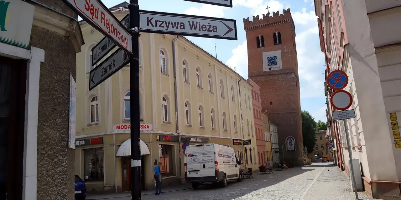 Ulica z wieżą i drogowskazami do Sądu Rejonowego, Krzywej Wieży i Zamku. Odkryj mało znane miejsca na Dolnym Śląsku.