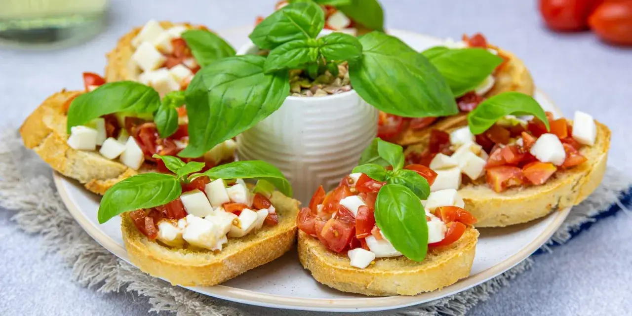 Bruschetta z pomidorami i mozzarellą – pyszny przepis na letnią przekąskę. Chrupiące grzanki z dodatkiem świeżej bazylii.