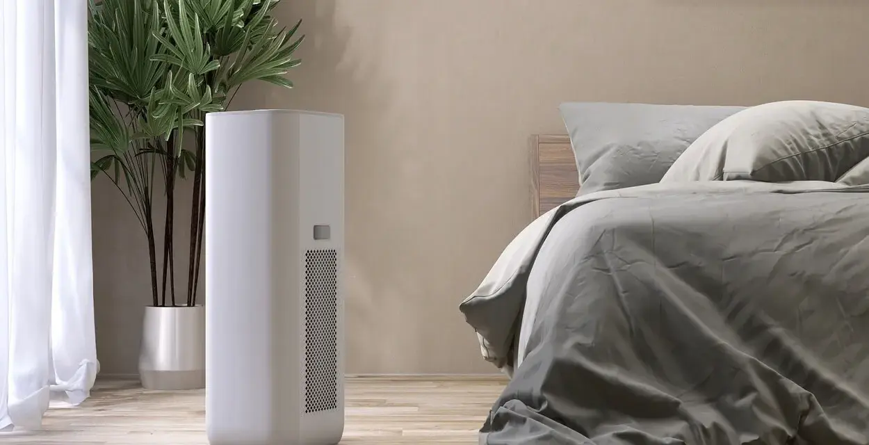 Un deumidificatore di notte, accanto a una pianta e un letto, crea un ambiente confortevole e salubre.