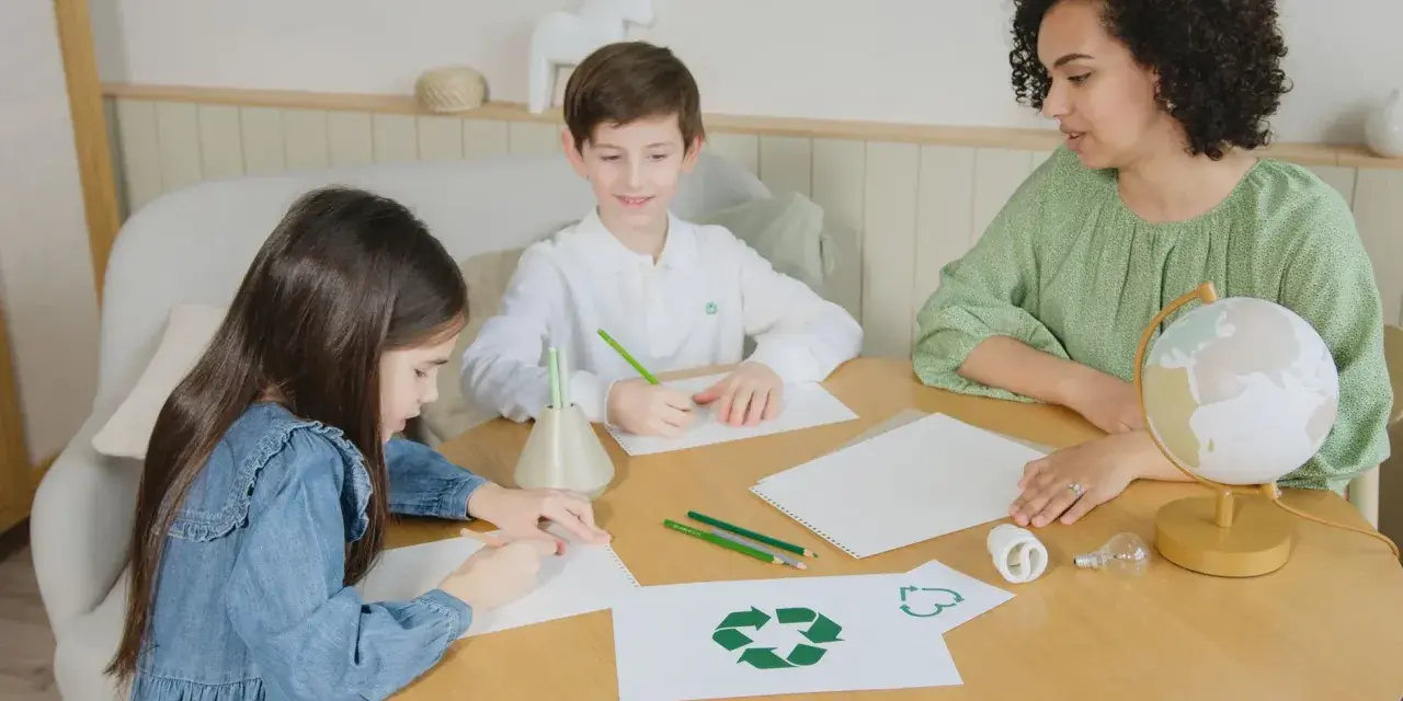 Dzieci i nauczycielka tworzą scenariusz zajęć "z ekologią na ty". Na stole symbol recyklingu, żarówki i globus.