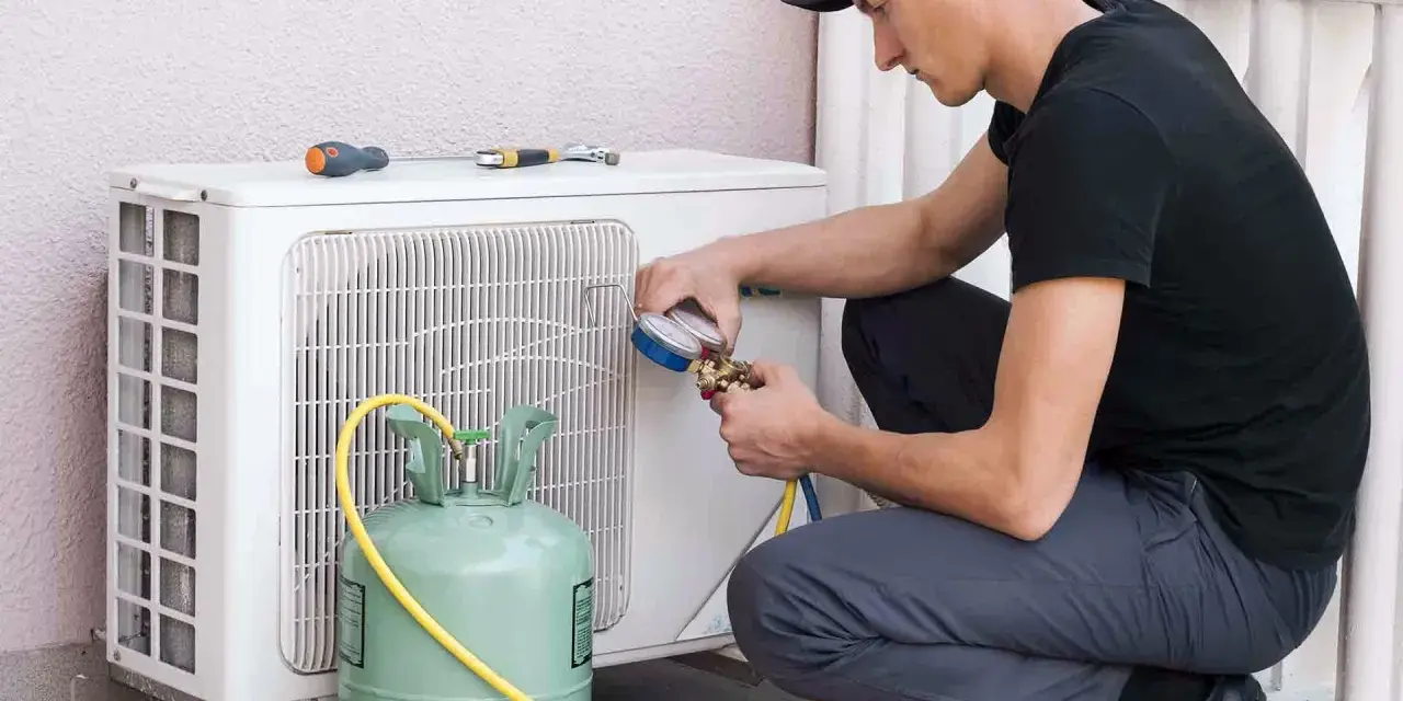 Técnico recargando gas aire acondicionado casa. Manómetro y tanque verde conectados a la unidad exterior.