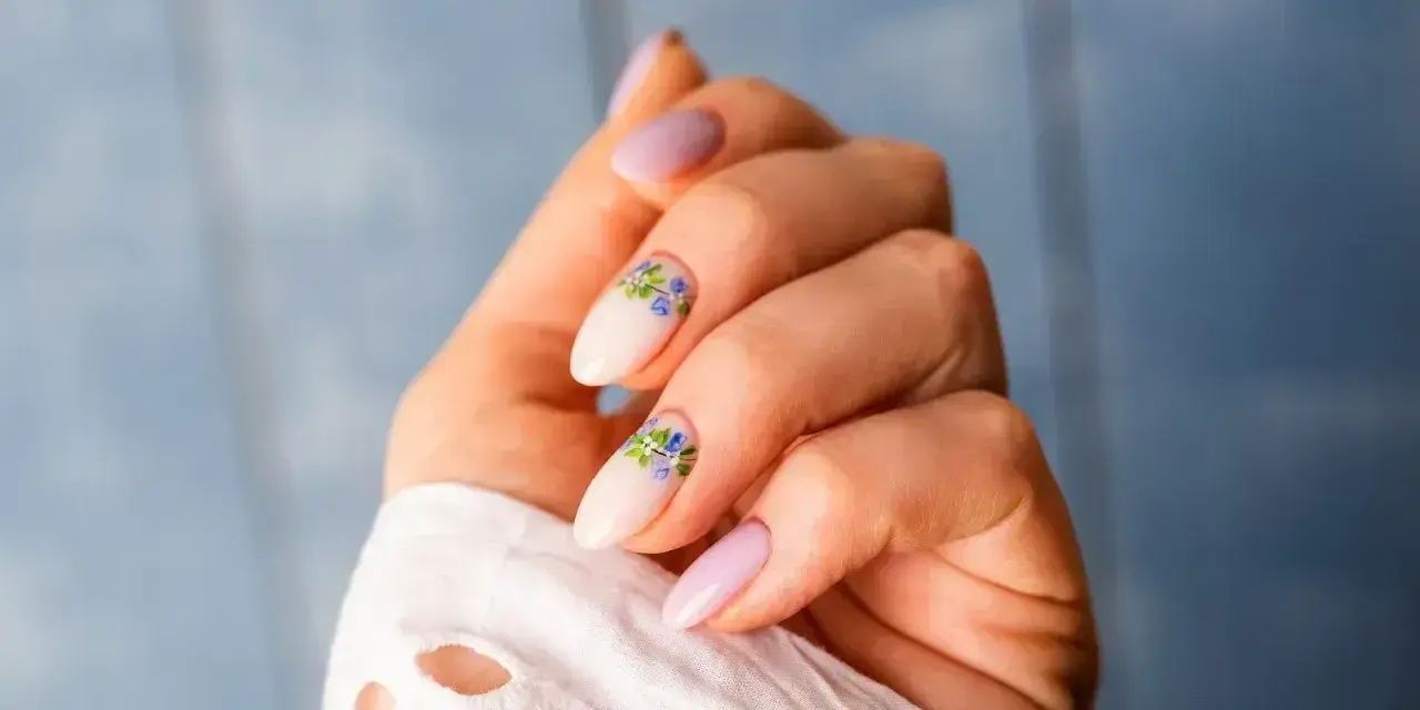 Delikatne, jasnoróżowe paznokcie z kwiatowym zdobieniem. Nawet przy łamliwych paznokciach można stworzyć piękny manicure.