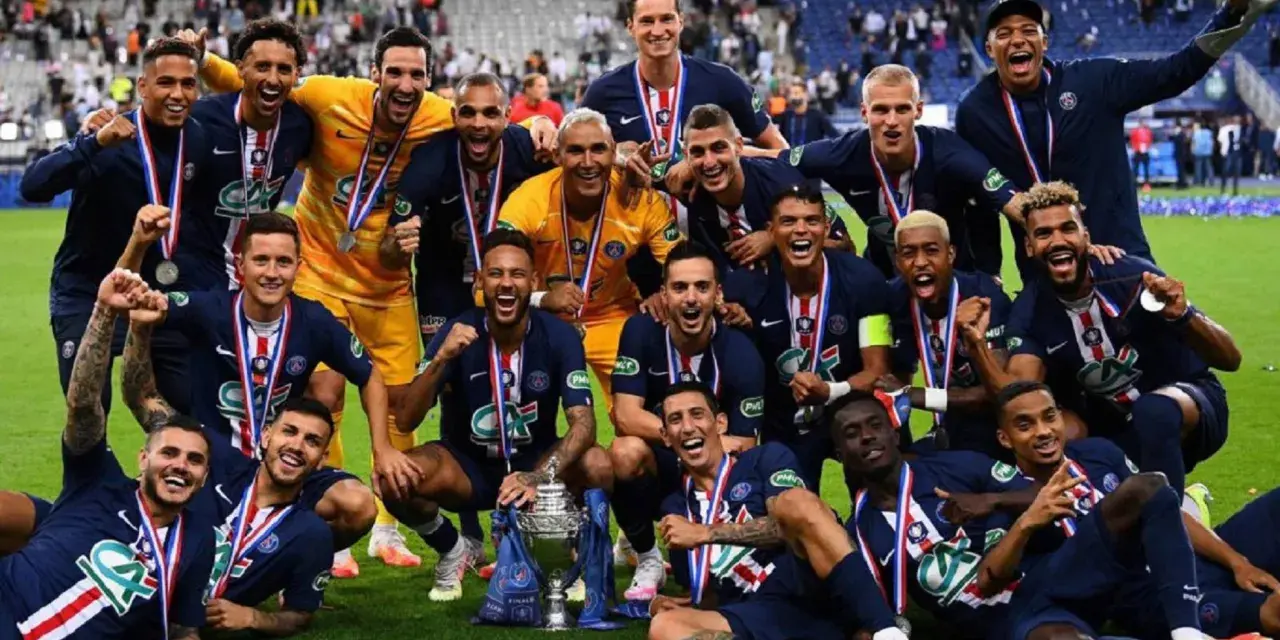 Un grupo de jugadores de Ligue 1 celebra con trofeos y medallas, sonriendo y vitoreando en el campo.