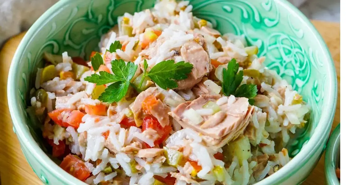 Reissalat mit Thunfisch, Tomaten und Gurken, garniert mit Petersilie, in einer grünen Schüssel. Ein leichter und leckerer Salat.