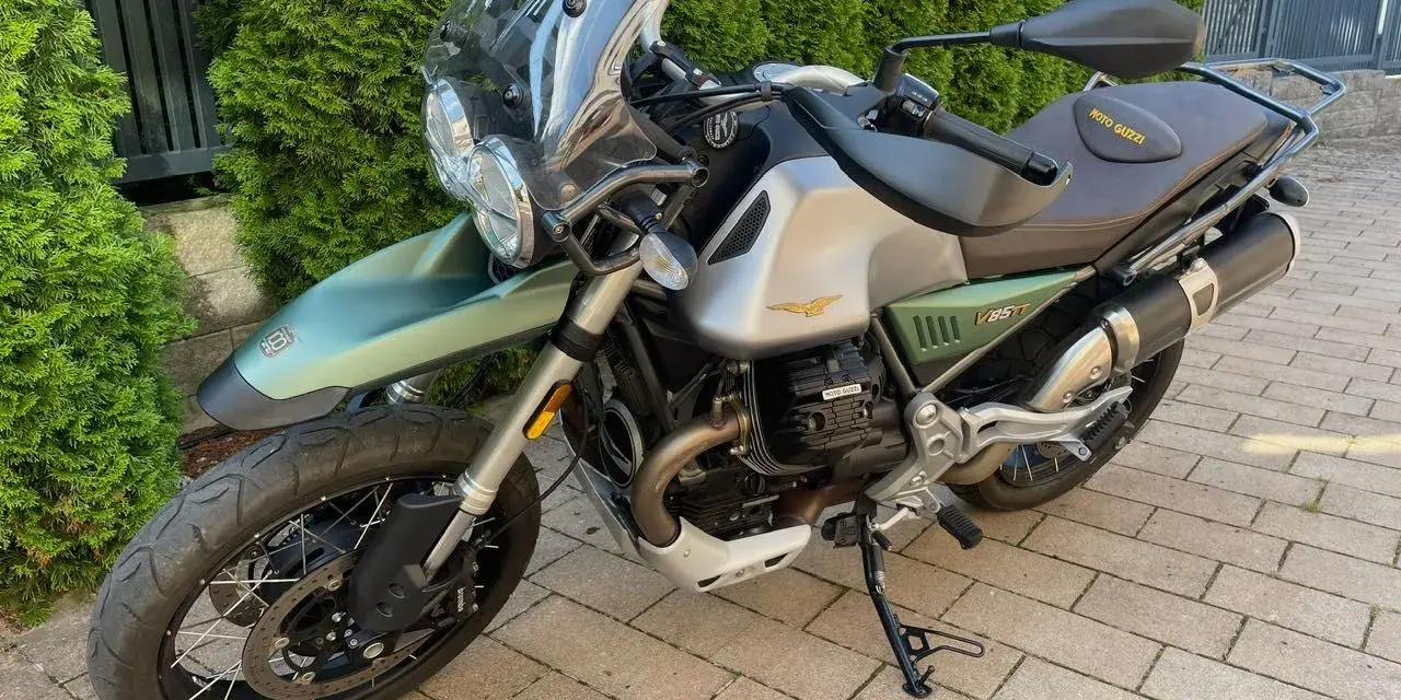 Zielony motocykl Moto Guzzi V85TT z silnikiem V, gotowy na przygodę.