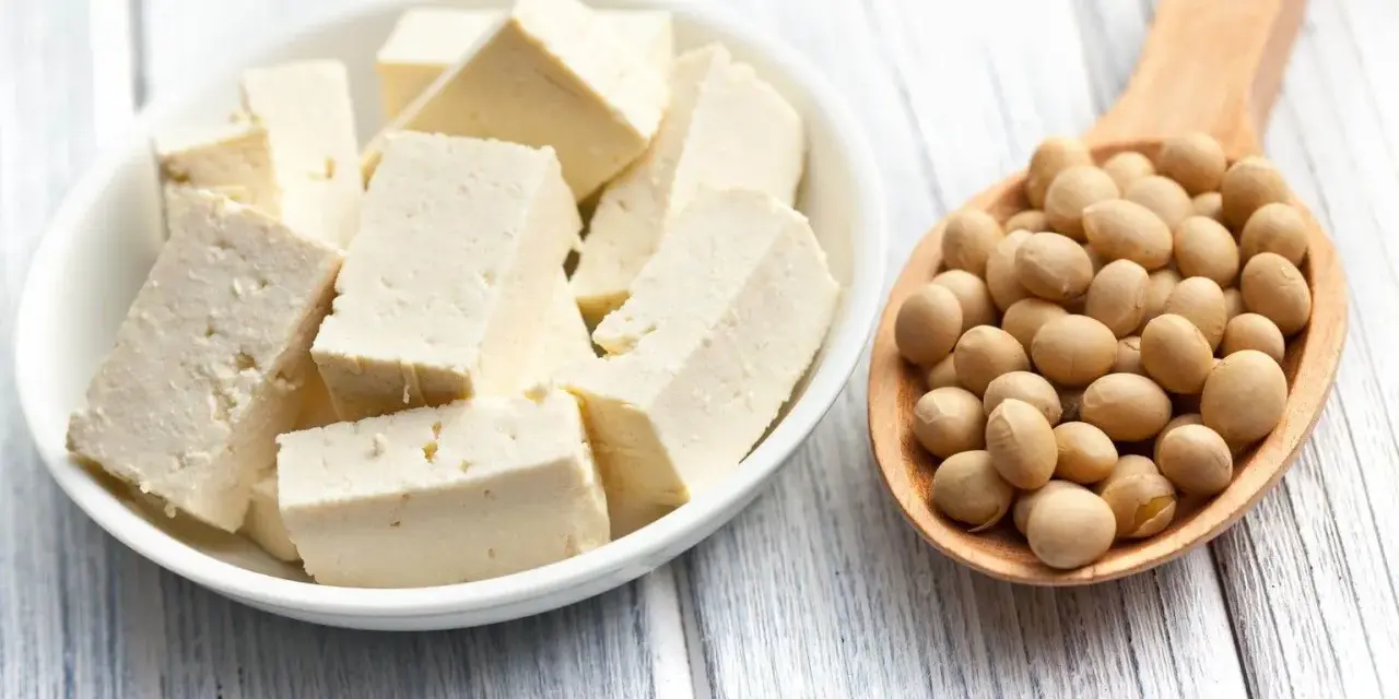 Kostki tofu w misce i łyżka pełna soi. Tofu co to? To produkt z soi, idealny do wegańskich dań.