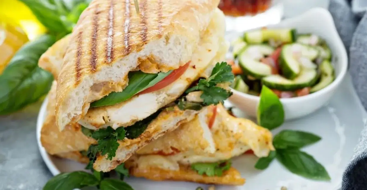 Pyszne panini z kurczakiem, pomidorem i bazylią, podane z sałatką z ogórka. Idealne na lekki lunch.