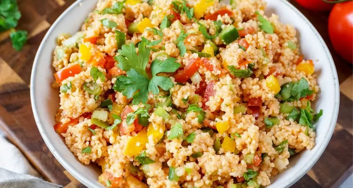 Bunter Couscous-Salat mit Tomaten, Paprika und frischer Petersilie, garniert mit einem Petersilienblatt.