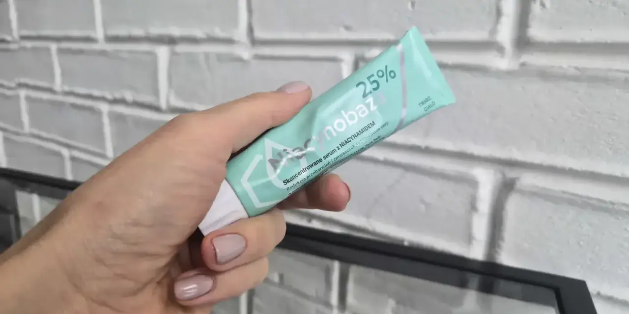 Dłoń trzyma tubkę serum niacynobaza 25%. Wiele pozytywnych opinii o tym produkcie.