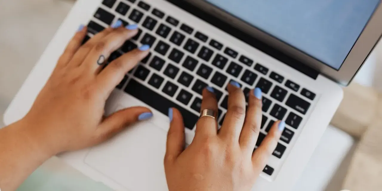 Mani che digitano su un laptop, forse per un corso di **università Pegaso**.