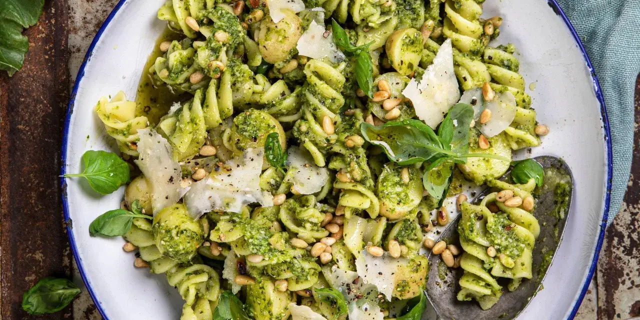 En närbild av en härlig pastasallad med pesto, pinjenötter, parmesan och färsk basilika. Perfekt för en lätt lunch.