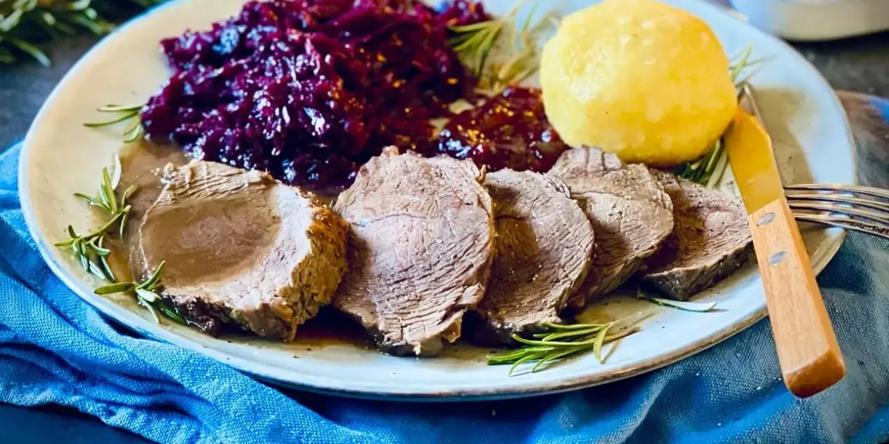 Saftiger Rinderbraten, serviert mit Rotkohl und Klößen – ein köstliches rinderbraten rezept für ein Festmahl.