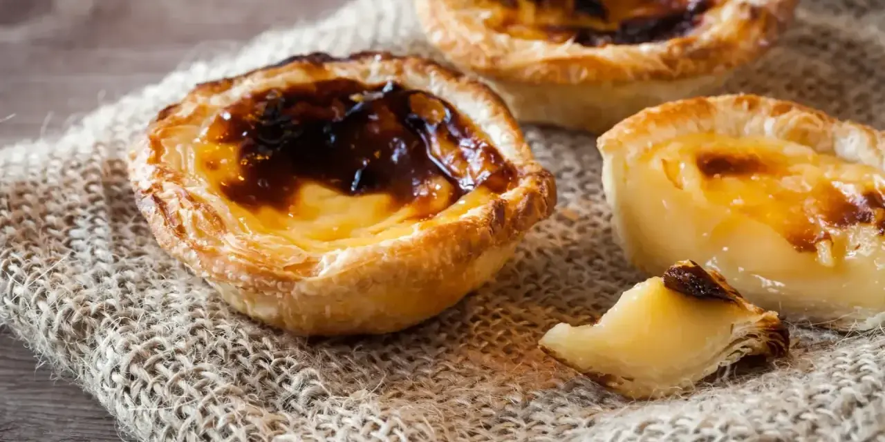 Tre krämiga portugisiska bakelser med karamelliserad yta, en klassiker inom portugisisk mat.