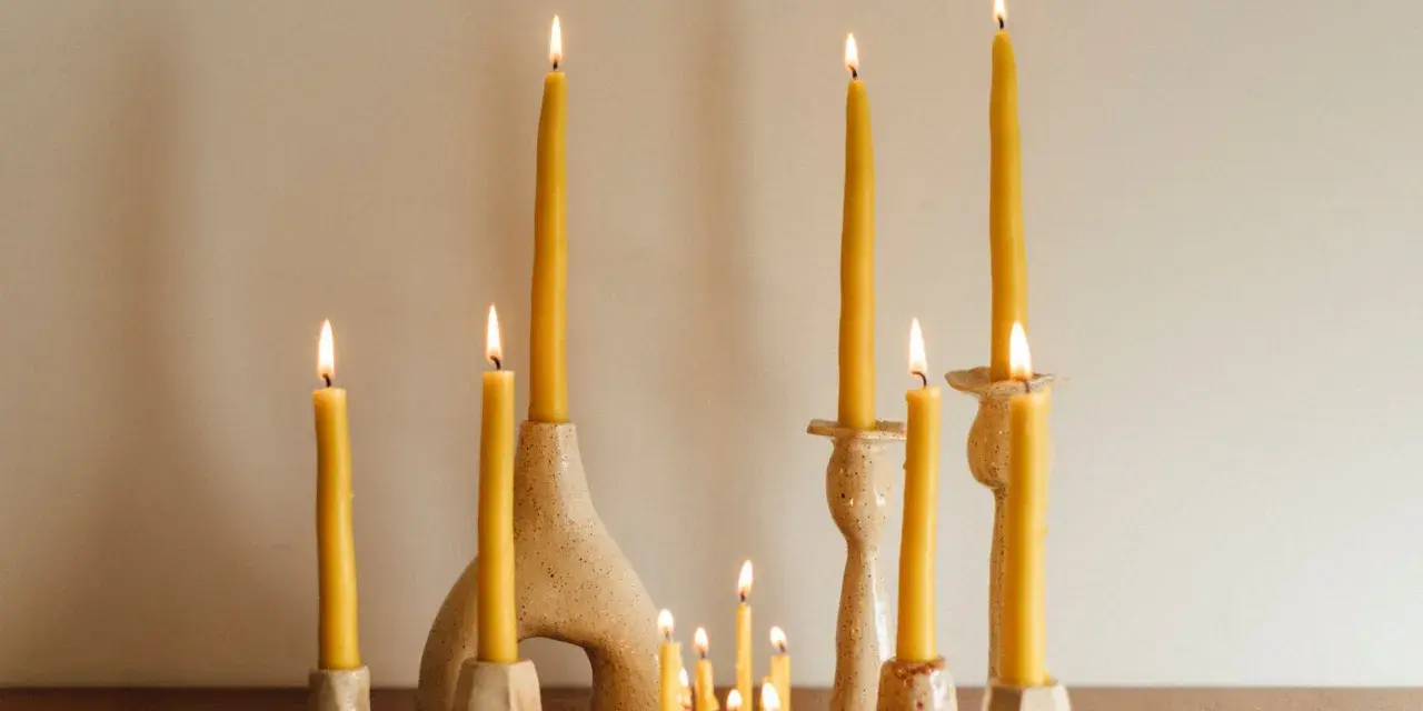 Velas amarillas de abeja en candelabros de cerámica. Una vela de palo santo para que sirve, ilumina el espacio con su suave resplandor.