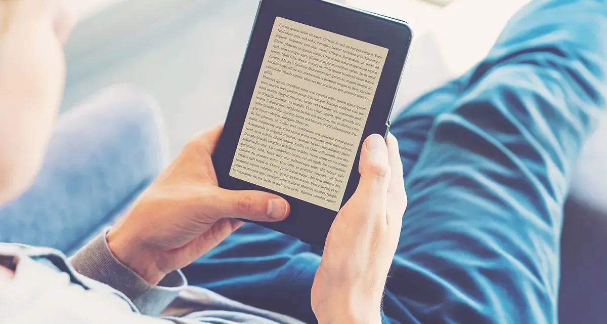 Osoba czyta książki na czytniku e-booków. Wygodny audiobook książki w cyfrowej formie.
