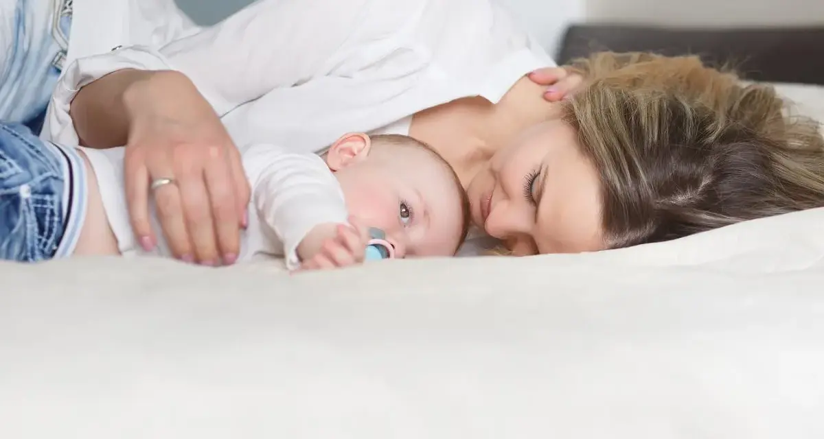 Mama tuli tuląca dziecko, ucząc się jak odkładać dziecko do łóżeczka, by spało spokojnie.