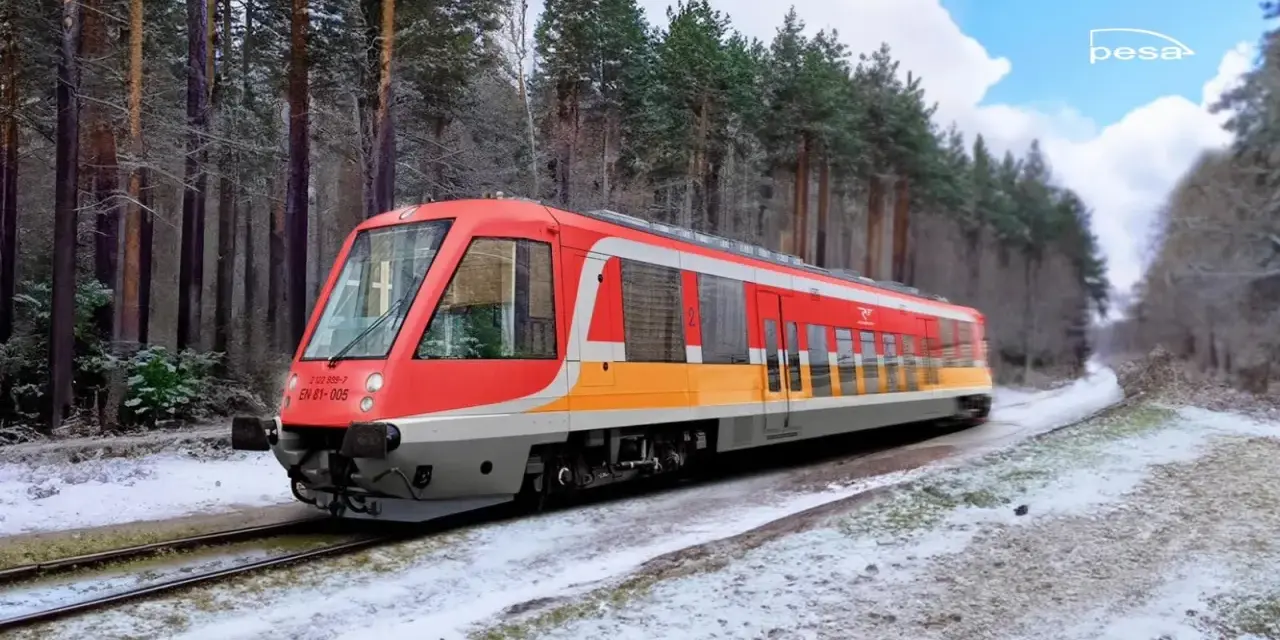 Czerwono-żółty pociąg EN 81-005 Polregio mknie przez zaśnieżony las.
