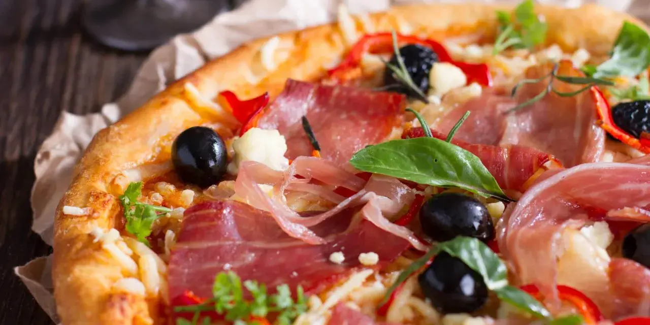 Pyszna pizza z cienko pokrojoną, aromatyczną szynką, czarnymi oliwkami i papryką. Idealna na każdą okazję!