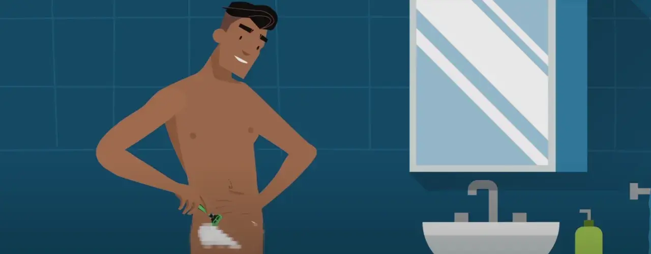 Hombre sonriente se afeita el vello púbico en el baño. Se ve su pene depilado.