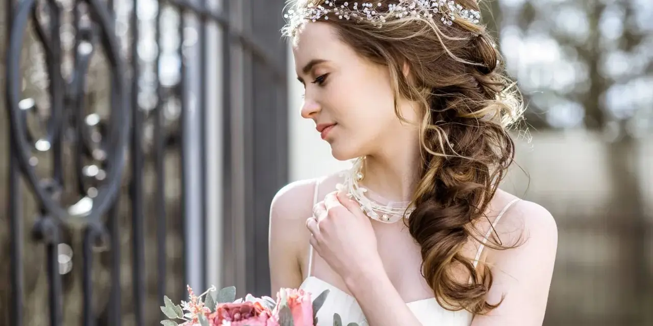 Upięta fryzura glamour z ozdobami z pereł i kryształków, delikatny bukiet róż i piwonii.