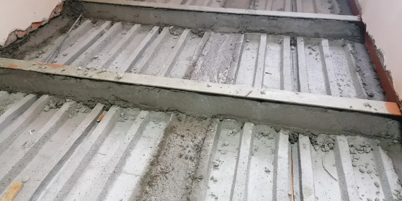Prace nad tym, jak wzmocnić strop w starym domu. Widoczne belki stropowe i betonowanie.