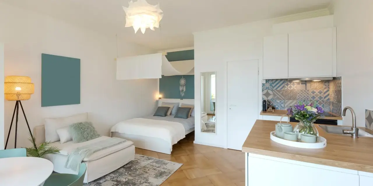 Gemütliche Wohnung einrichten: Bett, Sofa, Küche und Esstisch in einem hellen Raum.