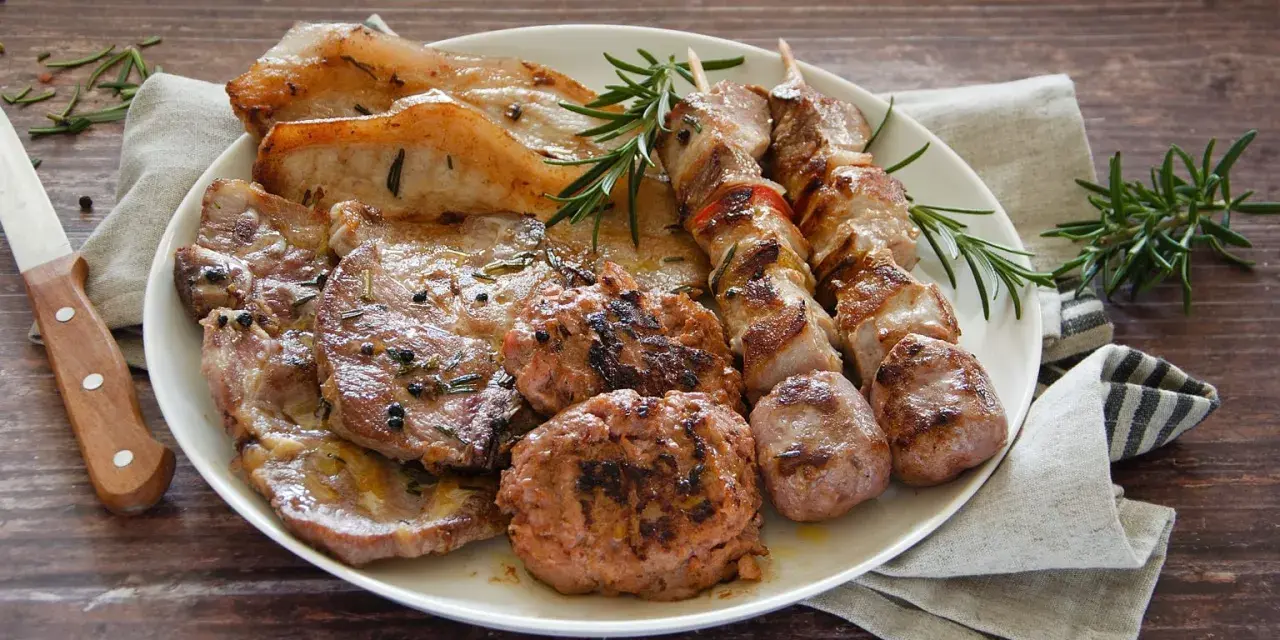 Un piatto invitante di grigliata di carne: costine, spiedini, salsicce e hamburger, guarniti con rosmarino fresco.