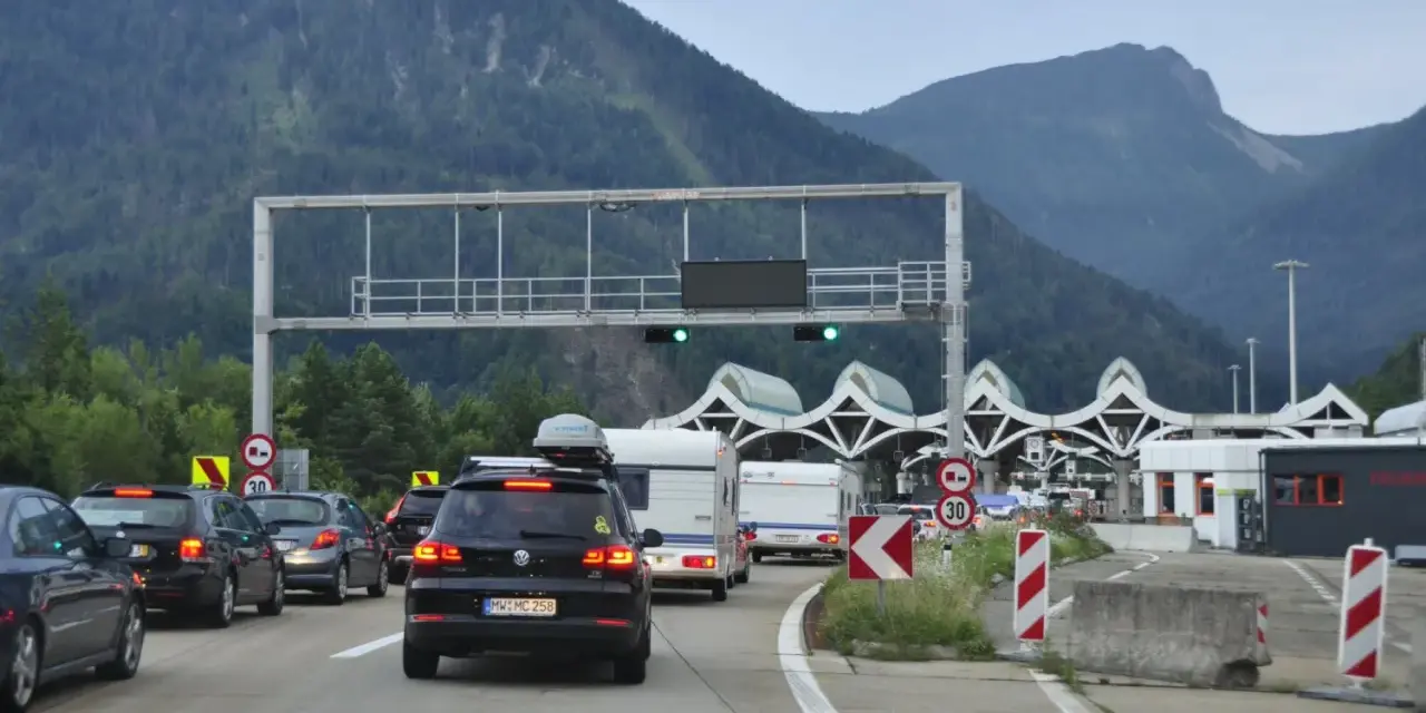 Korki na autostradzie przed punktem poboru opłat z widokiem na góry.