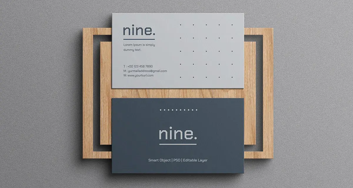 Dos tarjetas de visita minimalistas, una gris y otra azul oscuro, apiladas sobre un marco de madera.