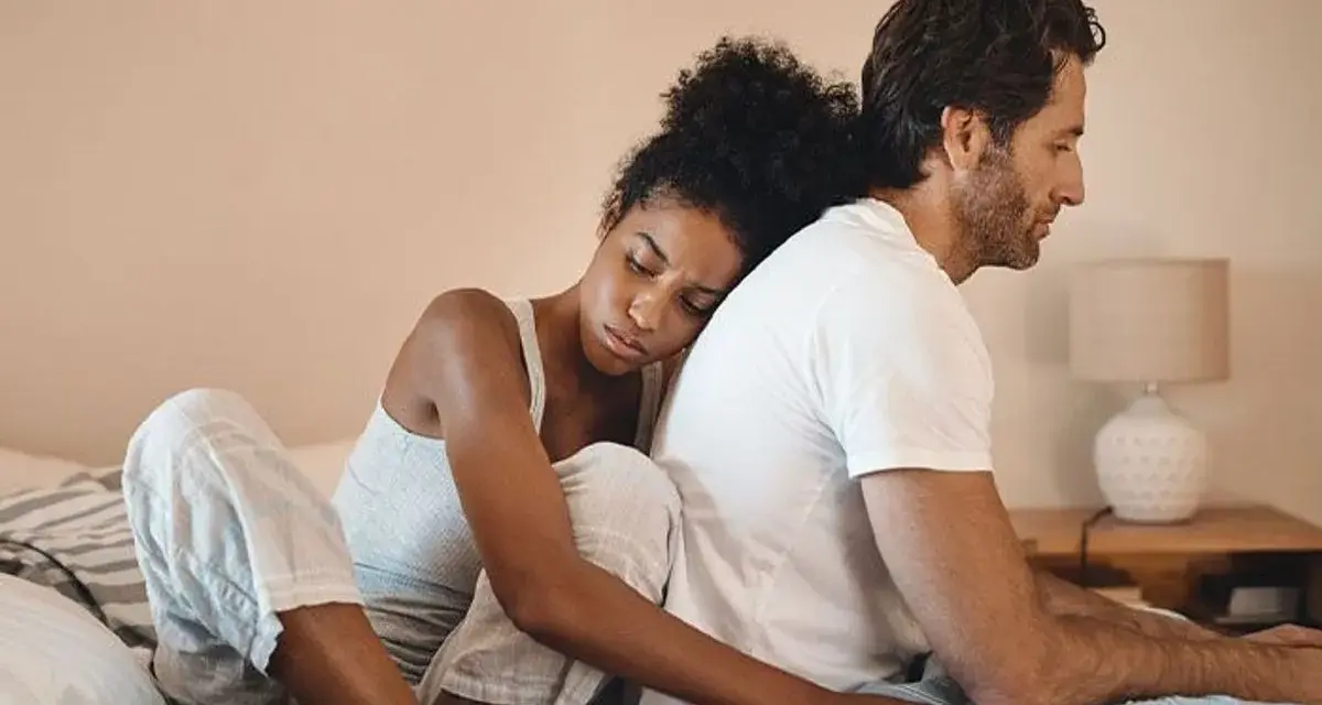 Un couple assis dos à dos sur un lit, l'air distant. On ne peut plus se parler sans s'engueuler.