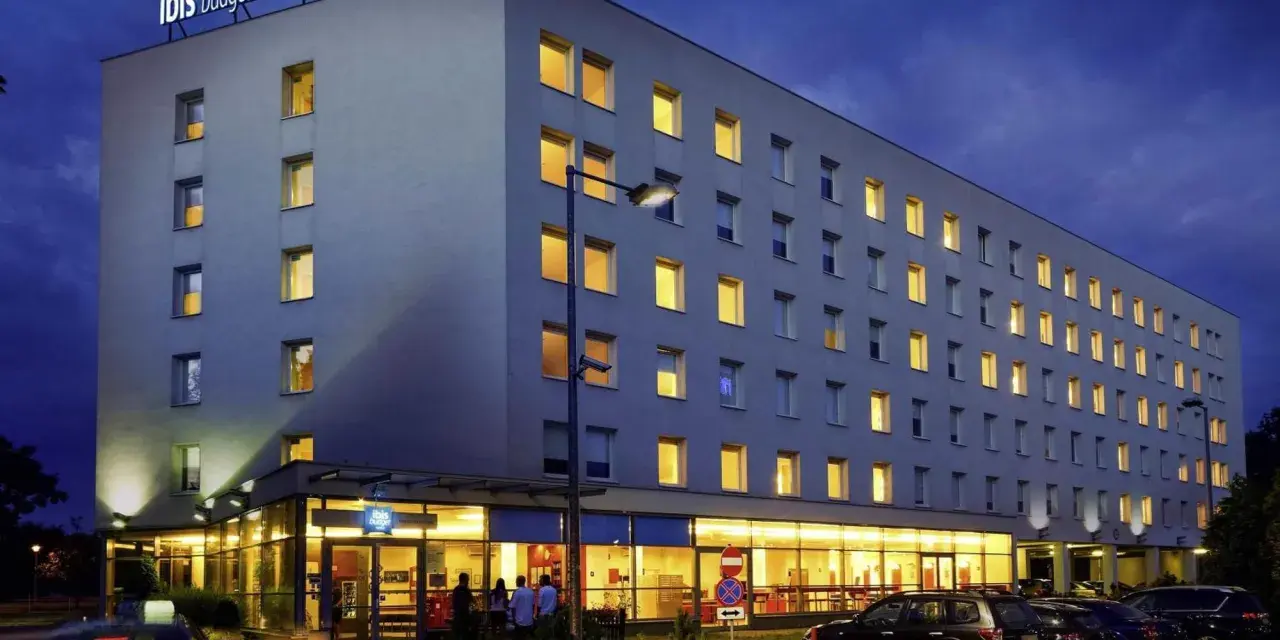 Ibis Budget Warszawa Centrum nocą. Hotel z podświetlanym logo, oknami i parkingiem.