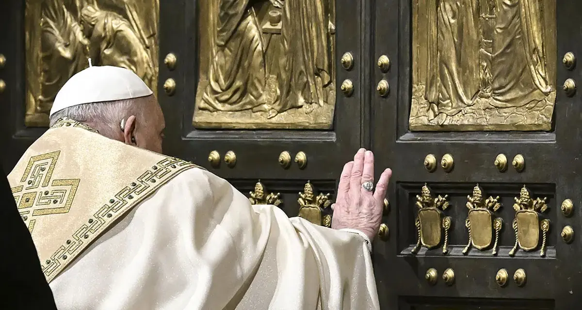 Papst Franziskus berührt die heilige Pforte des Petersdoms. Die bronzene Tür ist mit Reliefs verziert, die biblische Szenen darstellen.